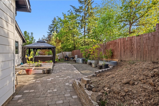 view of patio featuring a fenced backyard, a gazebo, and a garden