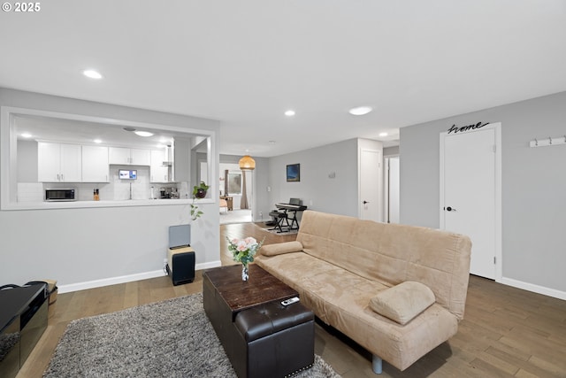 living room with recessed lighting, baseboards, and wood finished floors