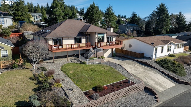 exterior space featuring driveway, a residential view, stairs, a deck, and a yard