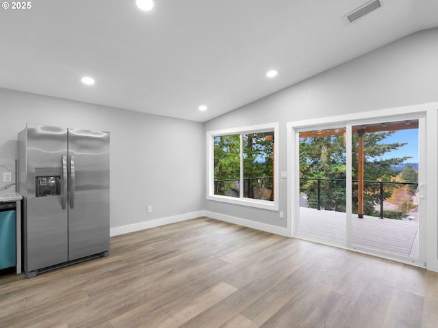 kitchen featuring stainless steel fridge, visible vents, vaulted ceiling, and light wood-style flooring