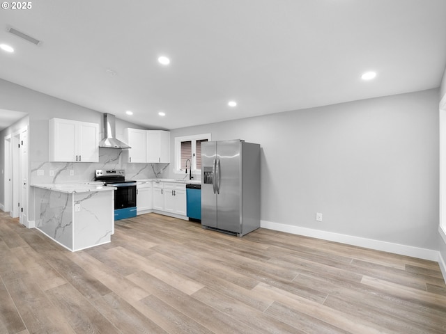 kitchen with light wood finished floors, stainless steel appliances, wall chimney range hood, and backsplash