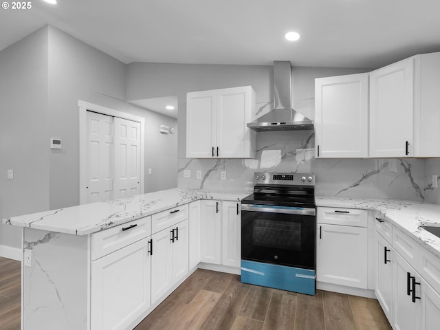 kitchen with a peninsula, wood finished floors, white cabinetry, electric stove, and wall chimney range hood