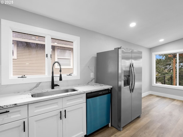 kitchen with a sink, white cabinets, dishwasher, light wood finished floors, and stainless steel fridge