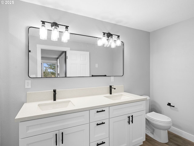 full bathroom with double vanity, wood finished floors, a sink, and toilet