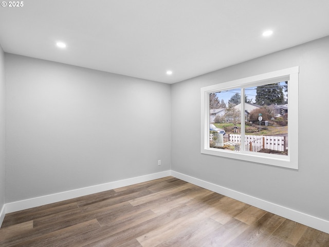 spare room with recessed lighting, wood finished floors, and baseboards