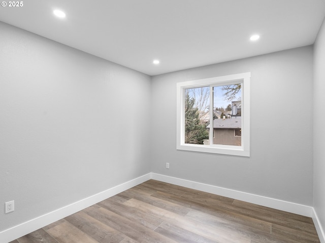 spare room featuring recessed lighting, wood finished floors, and baseboards