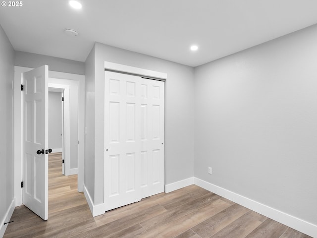 unfurnished bedroom with a closet, baseboards, and wood finished floors