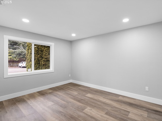 unfurnished room featuring baseboards, wood finished floors, and recessed lighting