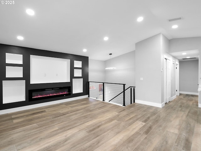 empty room with recessed lighting, visible vents, baseboards, light wood finished floors, and a glass covered fireplace