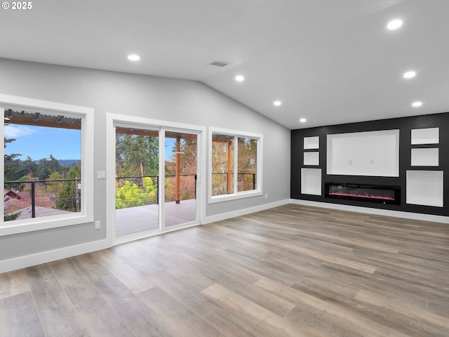 unfurnished living room featuring recessed lighting, wood finished floors, visible vents, vaulted ceiling, and a glass covered fireplace