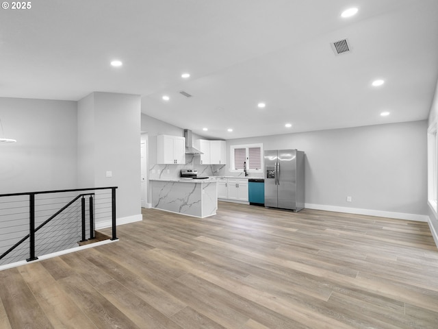 kitchen featuring light wood-style flooring, visible vents, white cabinetry, appliances with stainless steel finishes, and wall chimney range hood