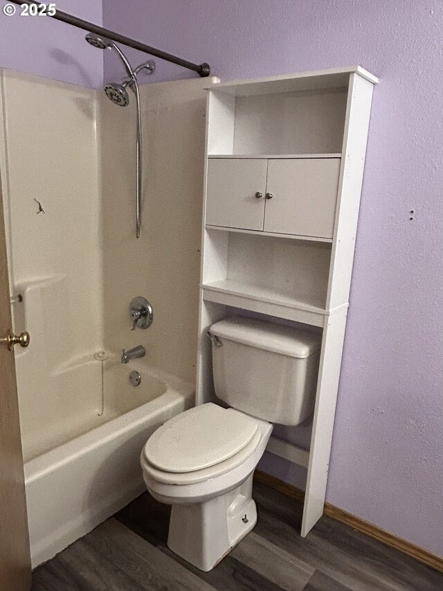bathroom with wood finished floors, toilet,  shower combination, and baseboards