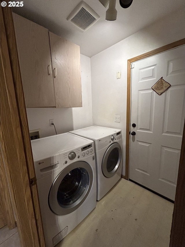 washroom with cabinet space, washing machine and dryer, and light wood-style flooring