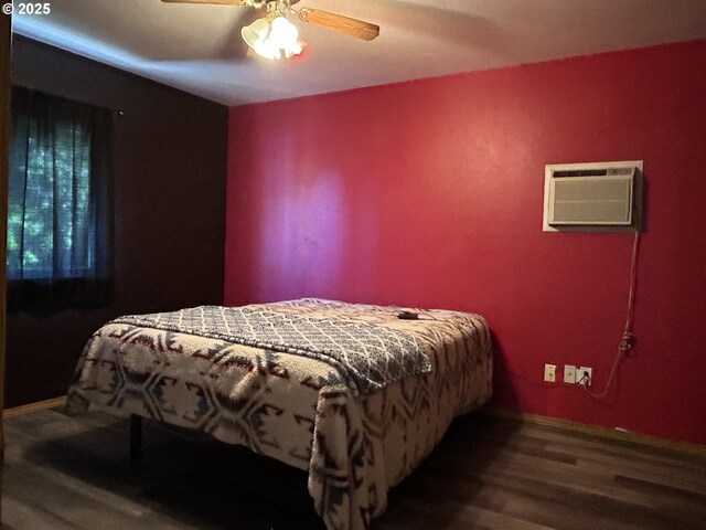 bedroom with wood finished floors, ceiling fan, an AC wall unit, and baseboards