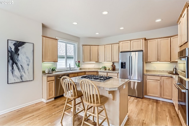 kitchen with light wood-style flooring, a center island, light brown cabinetry, and stainless steel appliances