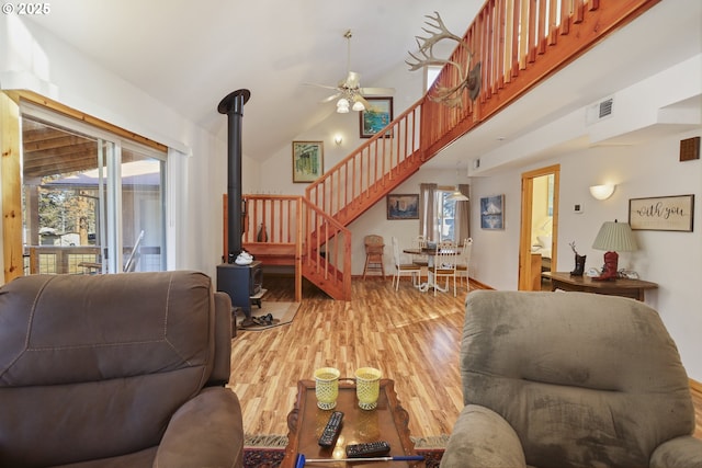 living room with hardwood / wood-style floors, high vaulted ceiling, a healthy amount of sunlight, and a wood stove