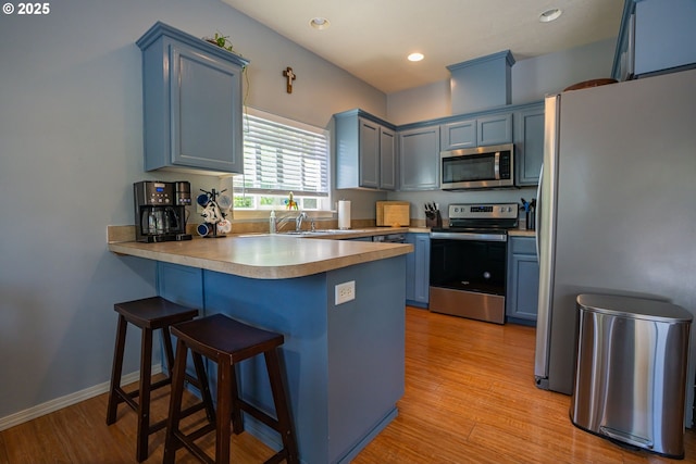 2872 Bluff Ave, Salem, OR 97302 - kitchen featuring stainless steel appliances, blue cabinets, a peninsula, a breakfast bar, and recessed lighting