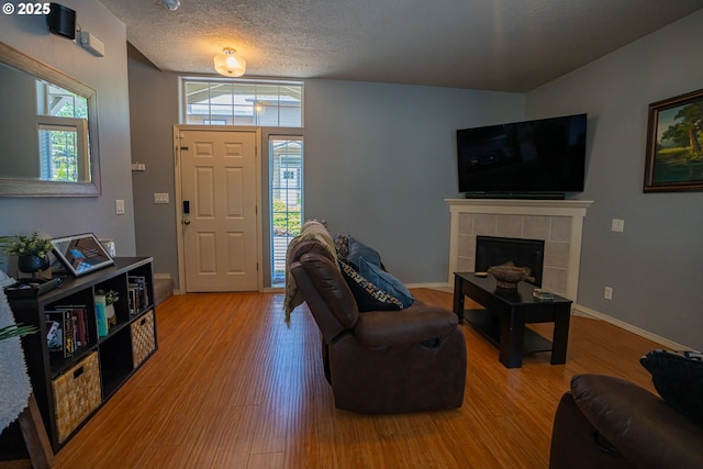 2872 Bluff Ave, Salem, OR 97302 - living room with wood finished floors, a tiled fireplace, baseboards, and a textured ceiling