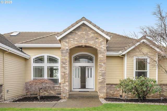 property entrance with a tile roof and brick siding