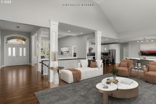 living room featuring dark wood finished floors, a notable chandelier, decorative columns, recessed lighting, and high vaulted ceiling