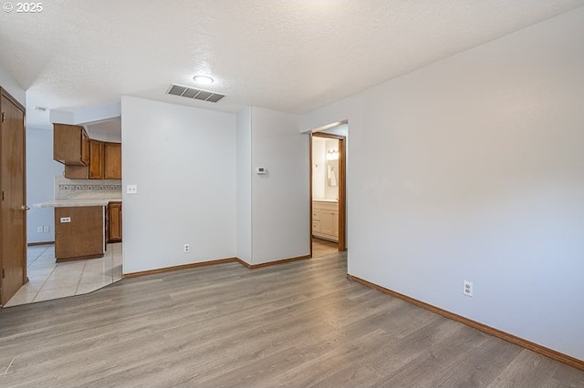 5270 Faircrest Ct SE, Salem, OR 97306 - unfurnished living room with light wood finished floors, a textured ceiling, baseboards, and visible vents