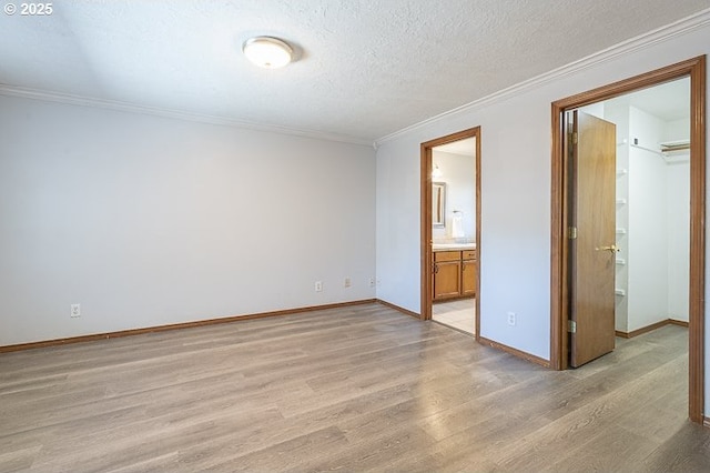 5270 Faircrest Ct SE, Salem, OR 97306 - unfurnished bedroom featuring crown molding, a textured ceiling, baseboards, light wood-style floors, and a spacious closet