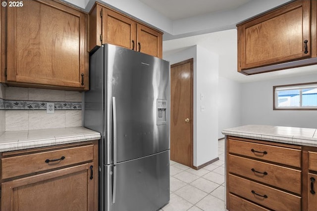 5270 Faircrest Ct SE, Salem, OR 97306 - kitchen featuring brown cabinetry, decorative backsplash, light tile patterned floors, and stainless steel refrigerator with ice dispenser