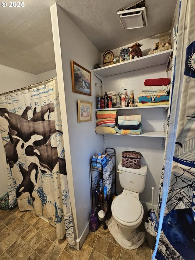 bathroom with a shower with curtain, a textured ceiling, and toilet