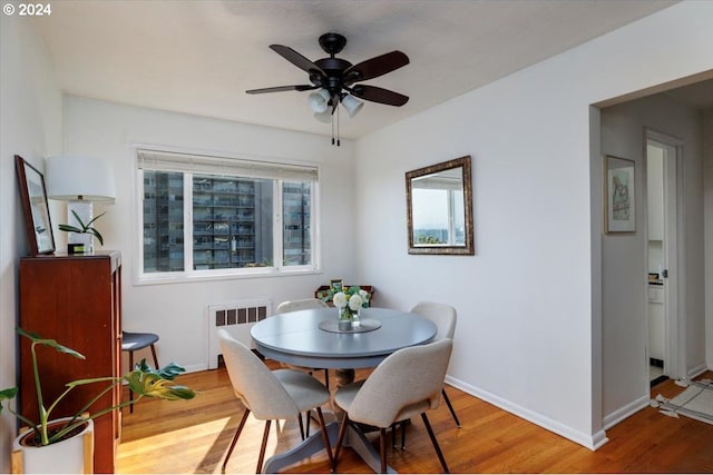 dining space with hardwood / wood-style flooring, ceiling fan, and radiator heating unit