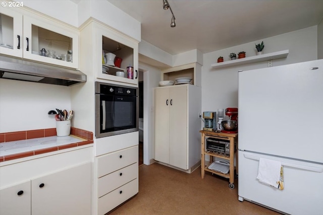 kitchen featuring white cabinetry, rail lighting, white fridge, stainless steel oven, and tile counters