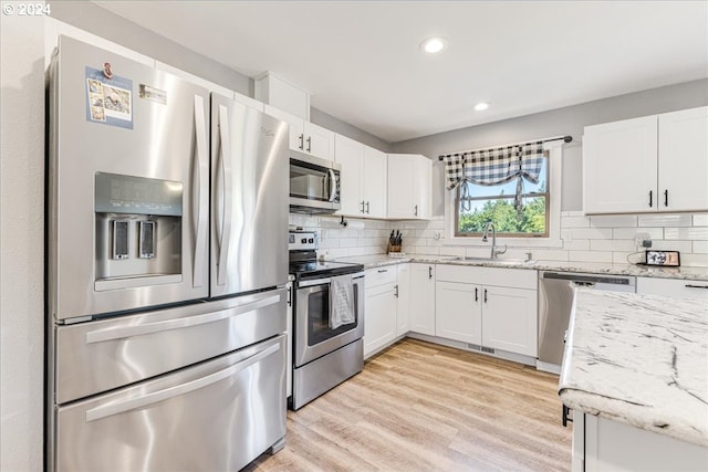 kitchen with white cabinetry, sink, light stone countertops, tasteful backsplash, and appliances with stainless steel finishes