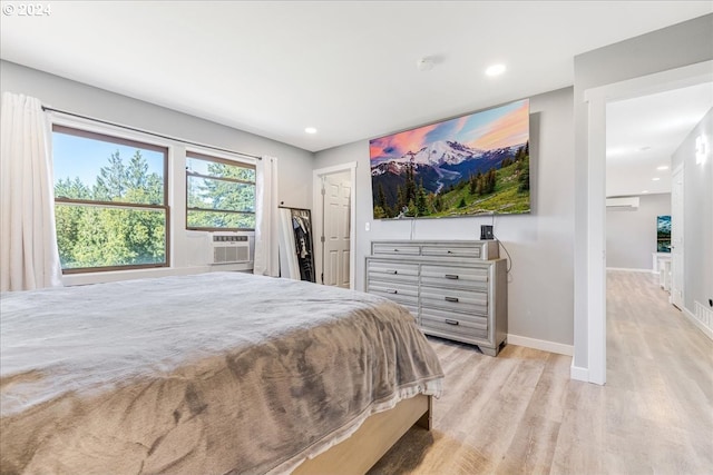 bedroom with cooling unit and light hardwood / wood-style flooring