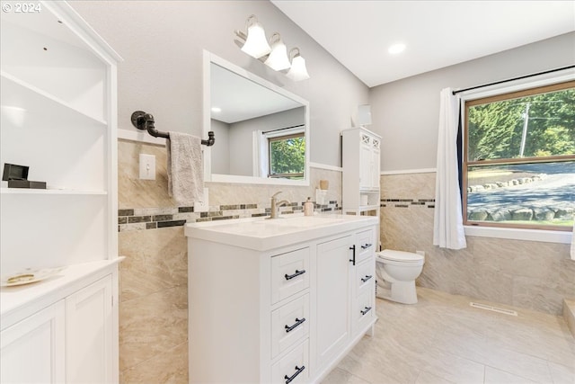 bathroom featuring tile patterned floors, vanity, a healthy amount of sunlight, and tile walls