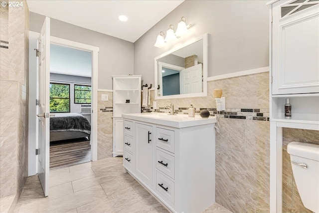 bathroom featuring tile patterned flooring, vanity, tile walls, and toilet