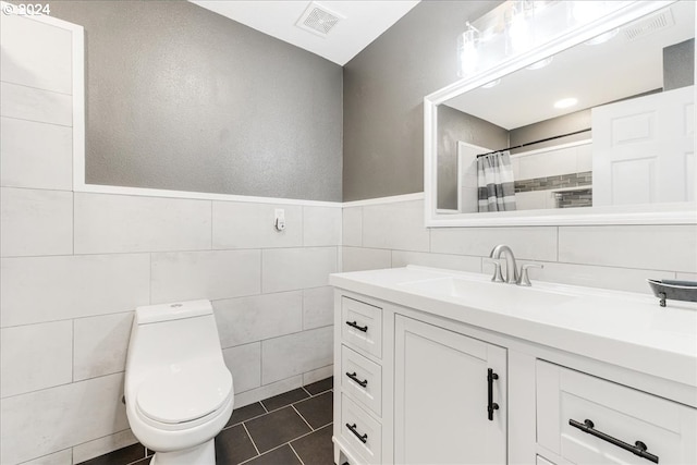 bathroom featuring vanity, tile patterned floors, a shower with curtain, toilet, and tile walls