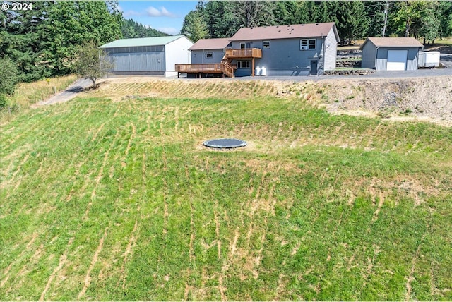 view of yard featuring a garage, an outbuilding, and a wooden deck