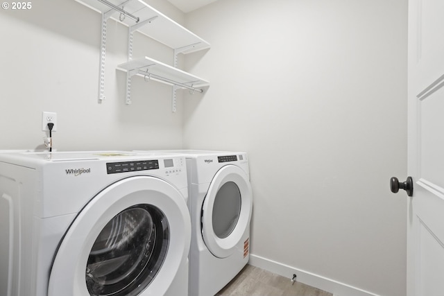laundry area with light wood finished floors, baseboards, washer and dryer, and laundry area