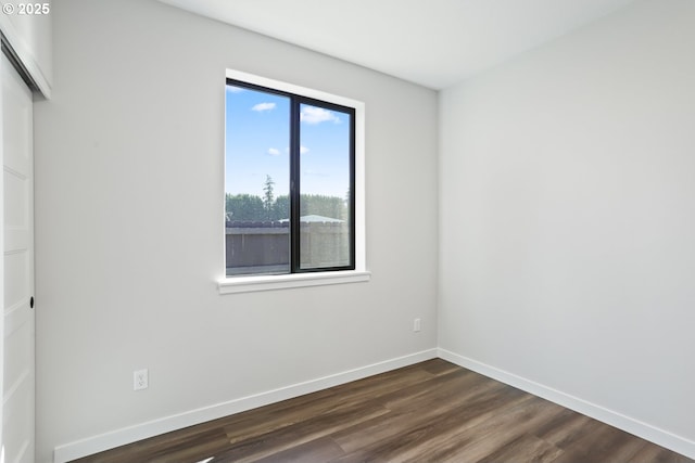 empty room with baseboards and dark wood-type flooring