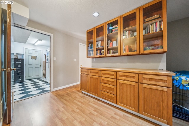 17476 SW Edy Rd, Sherwood, OR 97140 - kitchen featuring light countertops, light wood-style floors, glass insert cabinets, baseboards, and brown cabinetry