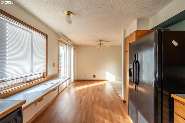 kitchen featuring visible vents, brown cabinets, a textured ceiling, light wood finished floors, and black refrigerator with ice dispenser