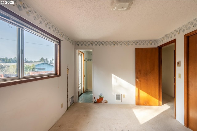 unfurnished room featuring visible vents, carpet floors, and a textured ceiling