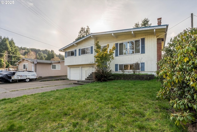 view of front of home with a chimney, driveway, an attached garage, and a front lawn