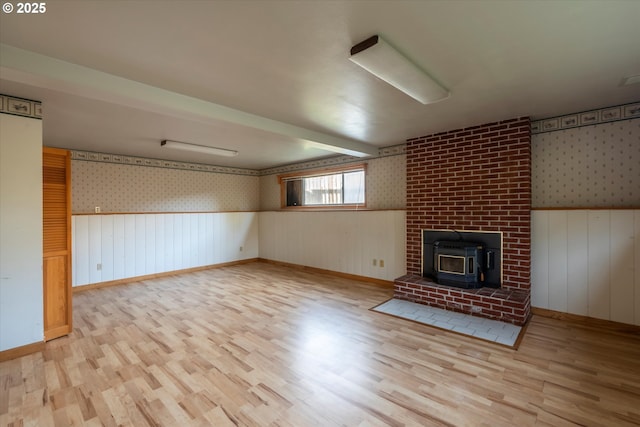 unfurnished living room with wallpapered walls, wood finished floors, and wainscoting