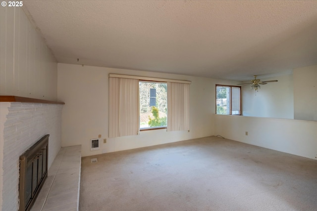 unfurnished living room with visible vents, light colored carpet, a fireplace, and a textured ceiling