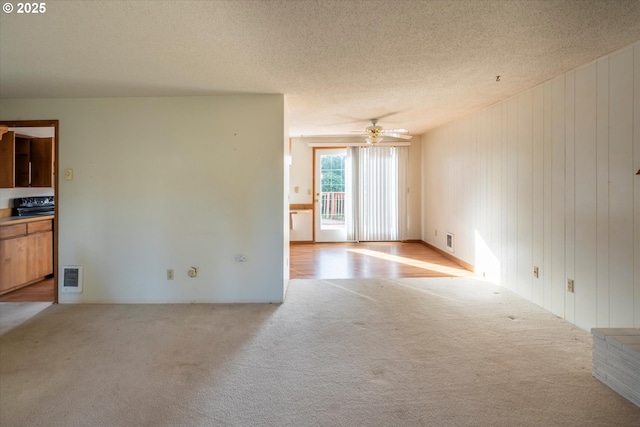 unfurnished room with visible vents, light colored carpet, a textured ceiling, and ceiling fan