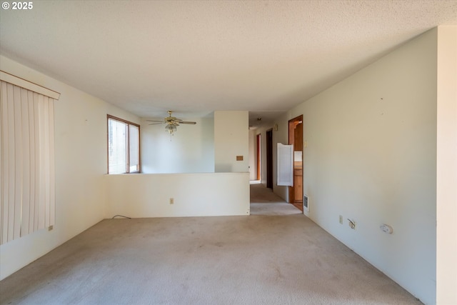 spare room with light colored carpet, visible vents, a textured ceiling, and a ceiling fan