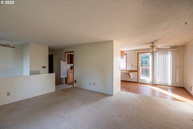 unfurnished living room with a ceiling fan, light colored carpet, and a textured ceiling