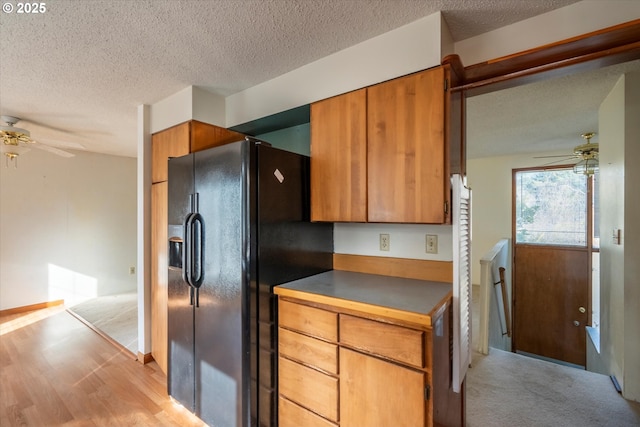 kitchen with black fridge with ice dispenser, brown cabinets, a textured ceiling, and ceiling fan