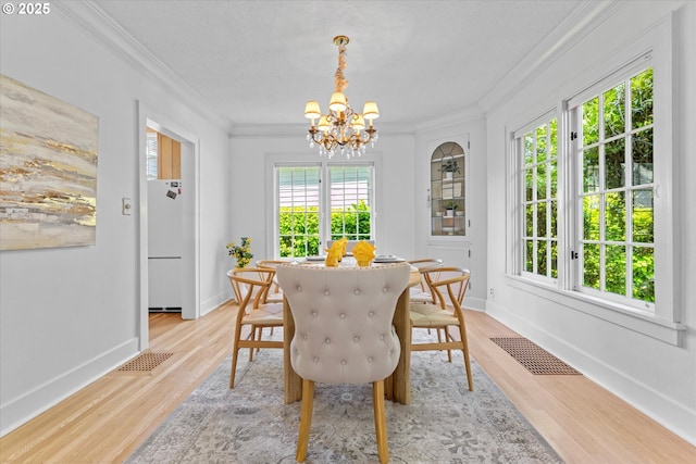 7311 SE 31st Ave, Portland, OR 97202 - dining space with healthy amount of natural light, a chandelier, crown molding, and light wood-style flooring