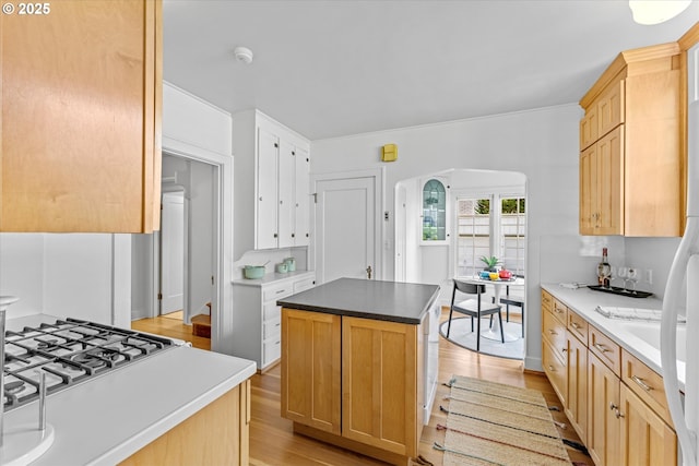 7311 SE 31st Ave, Portland, OR 97202 - kitchen with light wood-style flooring, arched walkways, a center island, stainless steel gas cooktop, and light brown cabinets